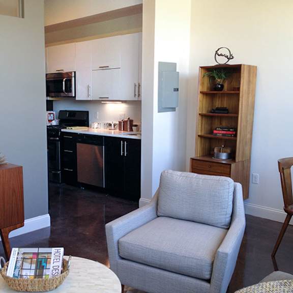 a living room with a grey chair and a wooden cabinet.